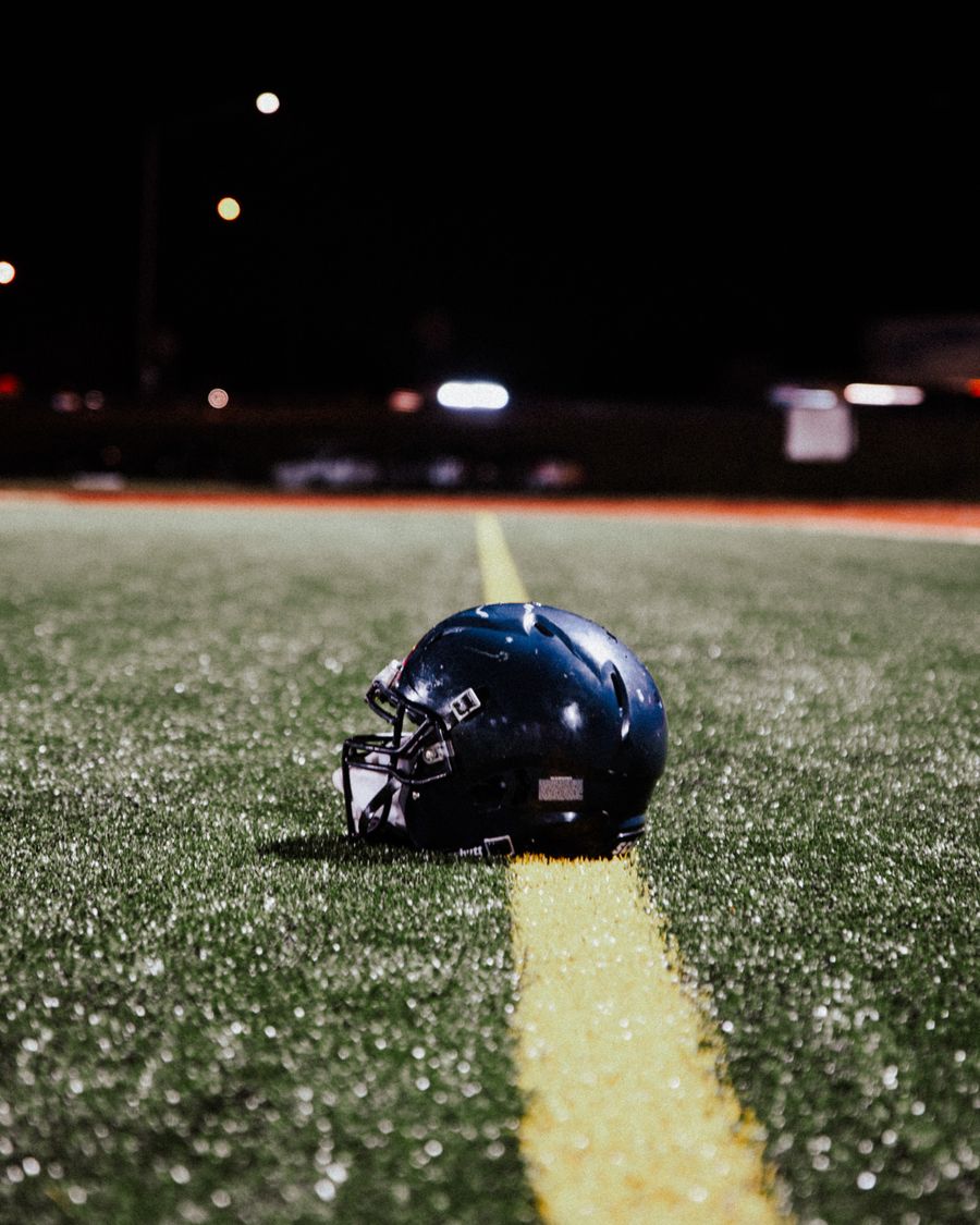 American football helmet resting on a yard line under floodlights at night